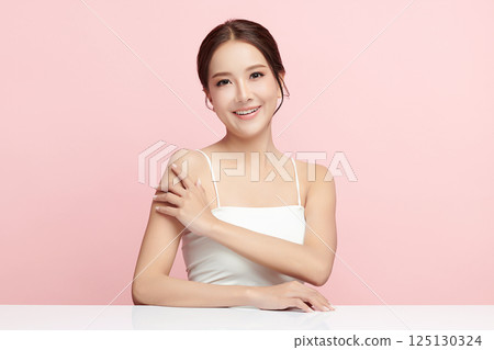 A beautiful young Asian woman with clean, fresh skin against a pink background. Skincare, facial treatment, cosmetology, beauty, and spa. An elegant portrait of an Asian woman. 125130324