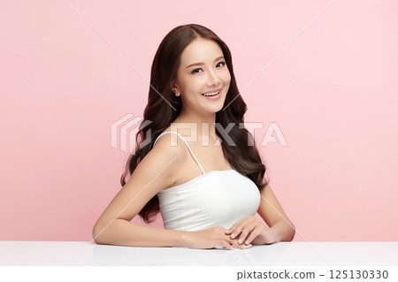 A beautiful young Asian woman with clean, fresh skin against a pink background. Skincare, facial treatment, cosmetology, beauty, and spa. An elegant portrait of an Asian woman. 125130330