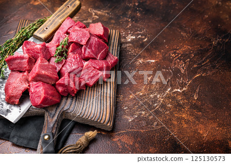Diced Raw Boar meat, uncooked Game Meat on butcher cutting board. brown background. top view Diced Raw Boar meat, uncooked Game Meat on butcher cutting board. brown background. top view 125130573