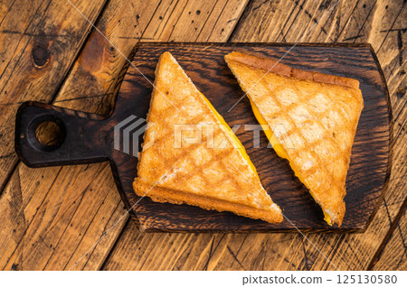 Toasted pressed cheese sandwich on wooden board. wooden background. top view Toasted pressed cheese sandwich on wooden board. wooden background. top view 125130580