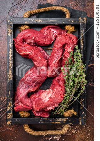 Beef cut Machete Skirt Steak, raw marble meat in wooden tray. black background. top view Beef cut Machete Skirt Steak, raw marble meat in wooden tray. black background. top view 125130581