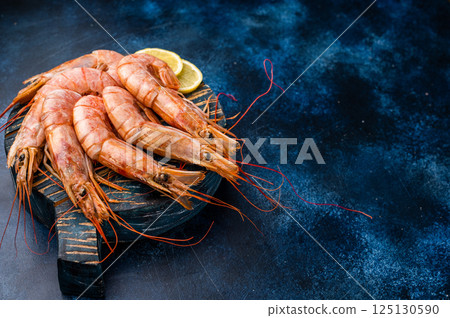 Ready for cooking Red Argentine shrimps, raw Prawns Langostino Austral on wooden board. blue background. top view Ready for cooking Red Argentine shrimps, raw Prawns Langostino Austral on wooden board. blue background. top view 125130590