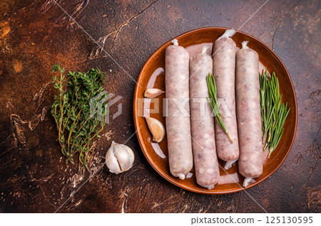 Raw Sausages with forcemeat mincemeat with herbs in plate. brown background. top view Raw Sausages with forcemeat mincemeat with herbs in plate. brown background. top view 125130595