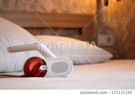 Housewife vacuuming white pillows on bed with handheld vacuum cleaner, close-up Housewife vacuuming white pillows on bed with handheld vacuum cleaner, close-up 125131193