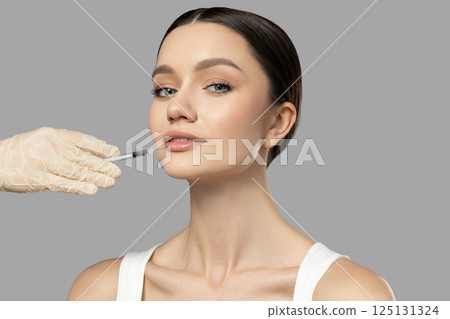 Botox. Skin Care. A girl gets a botox injection, on a light background. 125131324