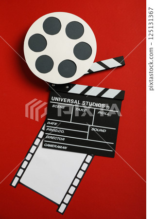 Clapperboard, reel and film on red background, top view 125131367