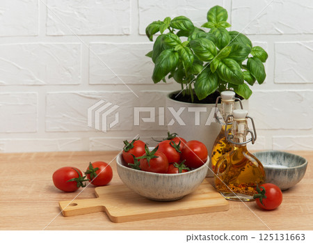 Cherry tomatoes and basil with olive oil on kitchen table Cherry tomatoes and basil with olive oil on kitchen table 125131663