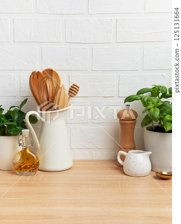 Kitchen utensils and ingredients resting on wooden countertop with white brick wall background Kitchen utensils and ingredients resting on wooden countertop with white brick wall background 125131664