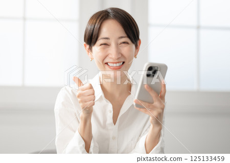 一個笑著操作智能手機的女人 一個笑著操作智能手機的女人 125133459