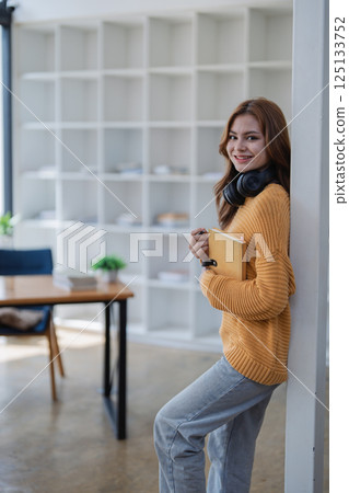happy young woman with headphones is immersed in a book, happily learning happy young woman with headphones is immersed in a book, happily learning 125133752
