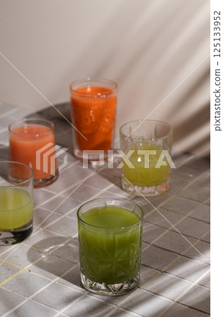Assortment Fresh Organic Juices Smoothies Colored Different Glasses Red Yellow Orange Green Fruits Vitamins Health Concept light grey tile Background Toned, palm shades, summer refreshments Assortment Fresh Organic Juices Smoothies Colored Different Glasses Red Yellow Orange Green Fruits Vitamins Health Concept light grey tile Background Toned, palm shades, summer refreshments 125133952