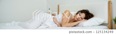 Young woman sleeping in cozy white bedroom interior peaceful morning nap calm girl relaxing on soft pillow clean bedding. wide web banner Young woman sleeping in cozy white bedroom interior peaceful morning nap calm girl relaxing on soft pillow clean bedding. wide web banner 125134249