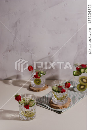 Healthy detox infused water with fruits. Refreshing summer homemade cocktail. water with strawberry, cucumber, kiwi. copyspace 125134863