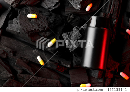 Black plastic jar and pills on dark background, space for text Black plastic jar and pills on dark background, space for text 125135141