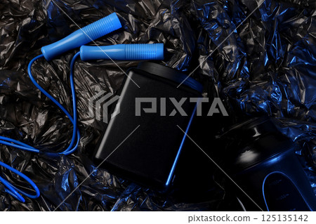 Jump rope, black plastic jar and bottle on dark background, top view 125135142