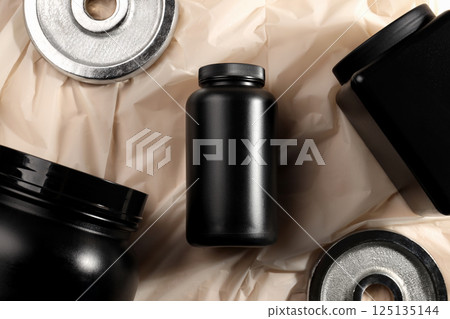 Black plastic jars and sport equipment on beige background, top view 125135144