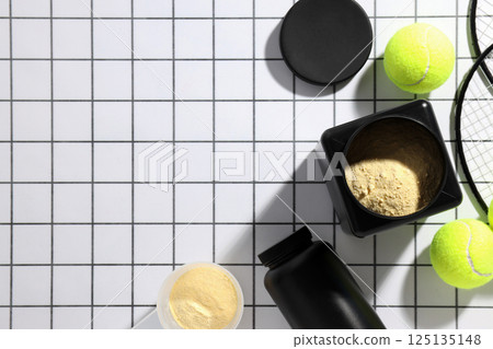 Black plastic jars, rackets and tennis balls on light background, space for text Black plastic jars, rackets and tennis balls on light background, space for text 125135148