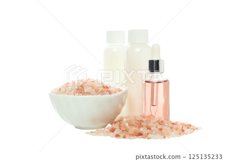 Pink sea salt and cosmetic bottles on white background, close up 125135233