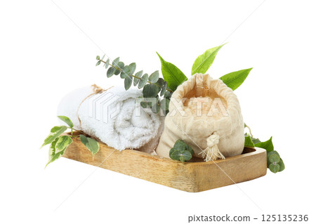 Towel, sea salt in bag and leaves on wooden board on white background, close up 125135236