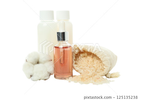 Sea salt in bag, cosmetic bottles and cotton flower on white background, close up 125135238