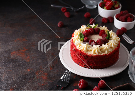 Red velvet cake on plate and bowls with berries on dark gray background, space for text Red velvet cake on plate and bowls with berries on dark gray background, space for text 125135330