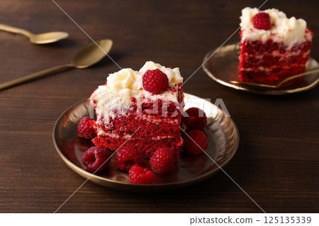 Pieces of red velvet cake on plates on wooden background, close up 125135339