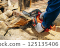 Cutting wood with a chainsaw 125135406