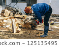 Cutting timber with a chainsaw 125135495