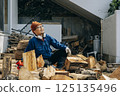 A man taking a break after cutting wood 125135496