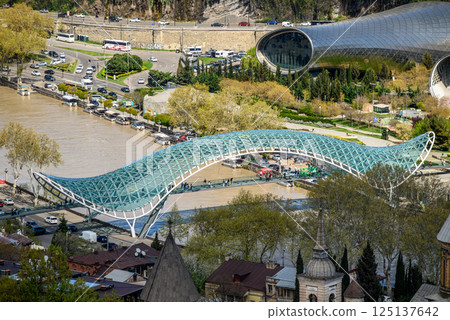 Peace bridge, steel and glass construction pedestrian bridge over Kura Mtkvari river in central Tbilisi, Georgia 125137642