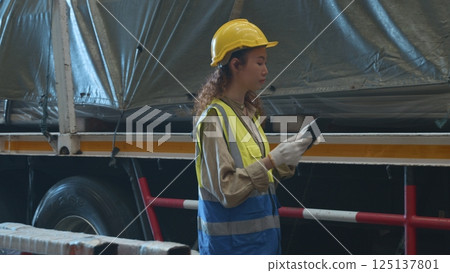 Industrial woman curly hair engineer wear safety uniform with hardhat checking metal sheet on cargo truck before shipment to customer in warehouse store factory workshop, logistics and transportation 125137801