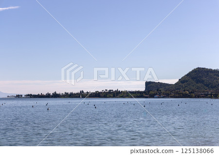 Lake Garda in Italy with clear view of shoreline and prominent silhouette of Rocca di Manerba Lake Garda in Italy with clear view of shoreline and prominent silhouette of Rocca di Manerba 125138066