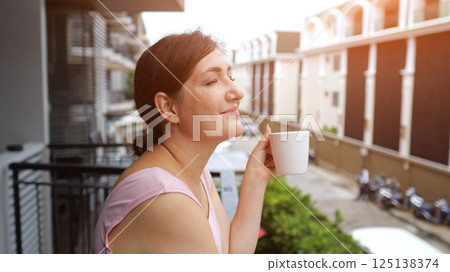 Woman enjoying morning coffee on hotel balcony Woman enjoying morning coffee on hotel balcony 125138374
