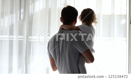 Father and daughter sharing a tender moment at hotel window 125138472