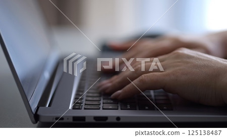 Woman opening and typing on laptop at hotel Woman opening and typing on laptop at hotel 125138487