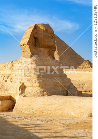 Giant Sphinx stands guard before the Great Pyramid under a clear blue sky in Giza, Egypt during midday Giant Sphinx stands guard before the Great Pyramid under a clear blue sky in Giza, Egypt during midday 125138490
