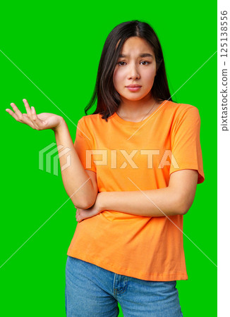 Woman with a questioning expression gestures thoughtfully in front of a bright green background Woman with a questioning expression gestures thoughtfully in front of a bright green background 125138556
