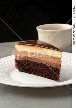 Sliced chocolate mousse cake displayed on a decorative plate beside a cup of coffee at a cozy cafe Sliced chocolate mousse cake displayed on a decorative plate beside a cup of coffee at a cozy cafe 125138620