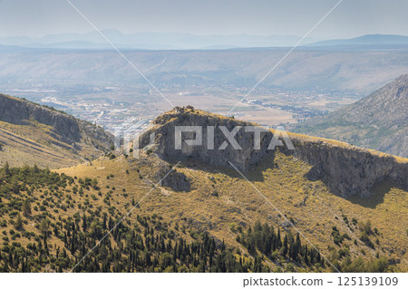 Landscape view from the Fortica hill, Bosnia and Herzegovina, Europe. Scenic view of a rugged mountain landscape with a distant town, showcasing nature's grandeur and serene beauty in the panorama. 125139109