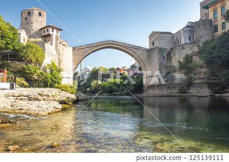 The Stari Most bridge, old bridge on Neretva river in Mostar town, Bosnia and Herzegovina, Europe. Iconic stone bridge arching over a river, blending history and architecture with natural beauty. 125139111