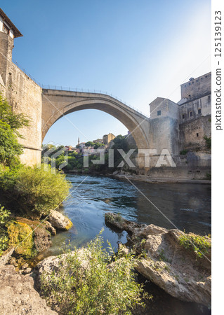 The Stari Most bridge, old bridge on Neretva river in Mostar town, Bosnia and Herzegovina, Europe. Majestic stone bridge gracefully arches over the tranquil river. 125139123