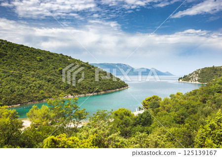 The sea coast of southern Dalmatia in Croatia, Europe. Coastal Serenity: Lush green hills meet crystal waters under a bright sky, a peaceful landscape beckons exploration and tranquility. The sea coast of southern Dalmatia in Croatia, Europe. Coastal Serenity: Lush green hills meet crystal waters under a bright sky, a peaceful landscape beckons exploration and tranquility. 125139167
