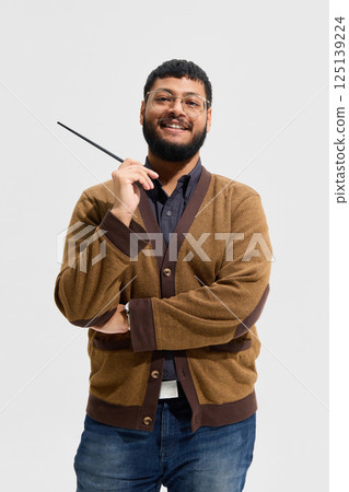 Portrait of smiling man, teacher in glasses and cardigan standing with pointer against white studio background. Portrait of smiling man, teacher in glasses and cardigan standing with pointer against white studio background. 125139224