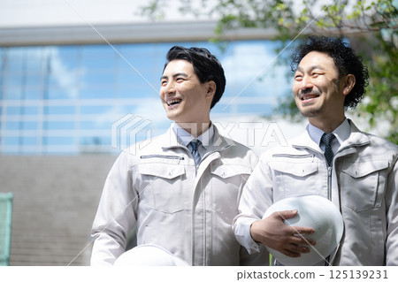 Image of a worker in work clothes looking up in front of a building, such as a construction manager 125139231