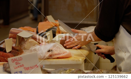 Fishmonger slicing tuna steak on cutting board in fish market 125139662