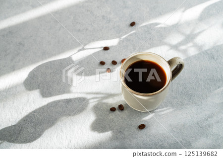 Cup of  coffee espresso on light textured background with coffee beans and morning light 125139682