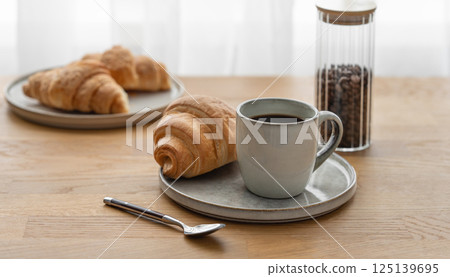 Cup of coffee espresso and croissants on a plate on a wooden table 125139695