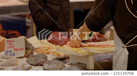 Fishmonger preparing fresh fish fillet on cutting board in seafood market 125139708