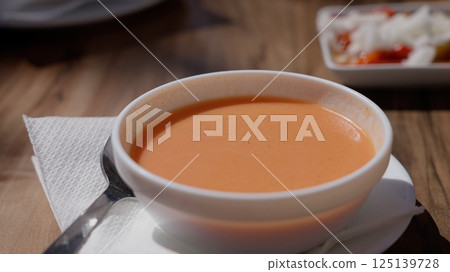 Gazpacho bowl with spoon on napkin, accompanied by a tapa Gazpacho bowl with spoon on napkin, accompanied by a tapa 125139728