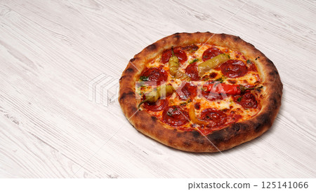 Baked pizza with sausage and pepper on a wooden textured gray table. Cooking. Restaurant advertising banner. Italian, spicy. Baked pizza with sausage and pepper on a wooden textured gray table. Cooking. Restaurant advertising banner. Italian, spicy. 125141066